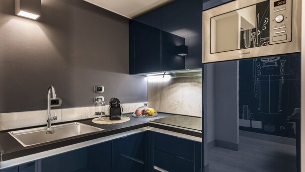 Una cucina moderna con lavello in acciaio inossidabile, forno a microonde integrato e macchina del caffè.