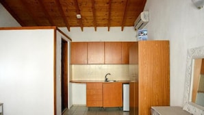 A compact kitchen with wooden cabinets, a sink, and a small countertop. - Yalis Studios (Skiathos)