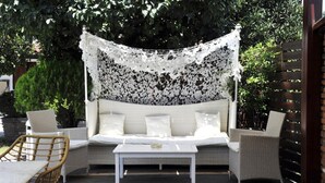 An outdoor seating area with a white wicker sofa, two white cushions, and a white coffee table. - Yalis Studios (Skiathos)