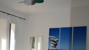 A bedroom with a bed, a ceiling fan, a window, and artwork on the wall. - Pozzo al Moro Village (Campo nell'Elba)