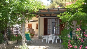 A patio with white chairs and a table, surrounded by potted plants and a wooden pergola. - Pozzo al Moro Village (Campo nell'Elba)