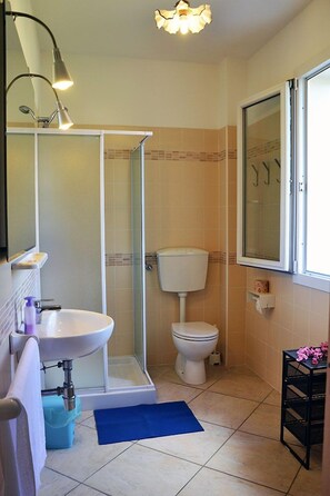 A bathroom with a white sink, a glass shower enclosure, a toilet, and a window. - Pozzo al Moro Village (Campo nell'Elba)