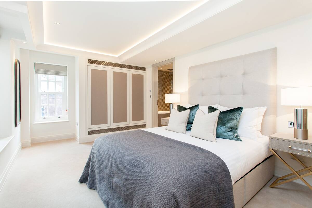 A modern bedroom with a large bed, a nightstand, and a wardrobe.