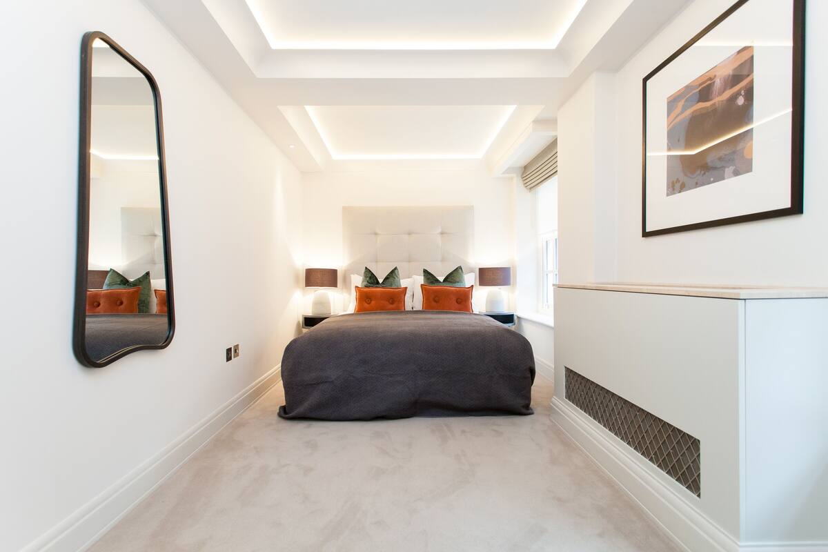 A modern bedroom with a large bed, a mirror, and a framed picture on the wall.