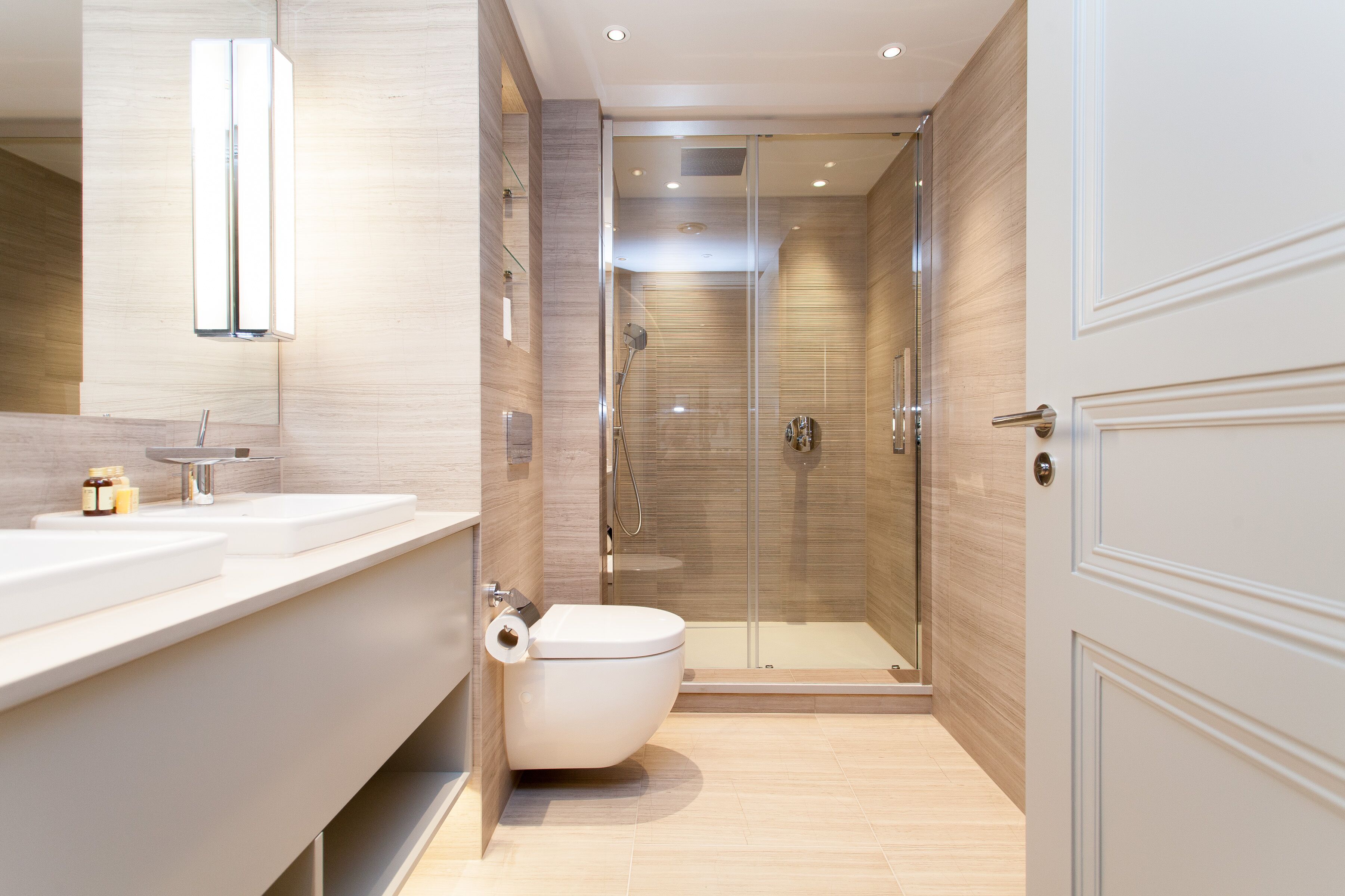 Un baño moderno con cabina de ducha de vidrio, inodoro y tocador con espejo.