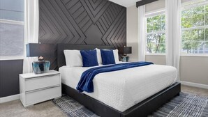 Een moderne slaapkamer met een groot bed, twee nachtkastjes en een hoofdeinde met een geometrisch patroon.