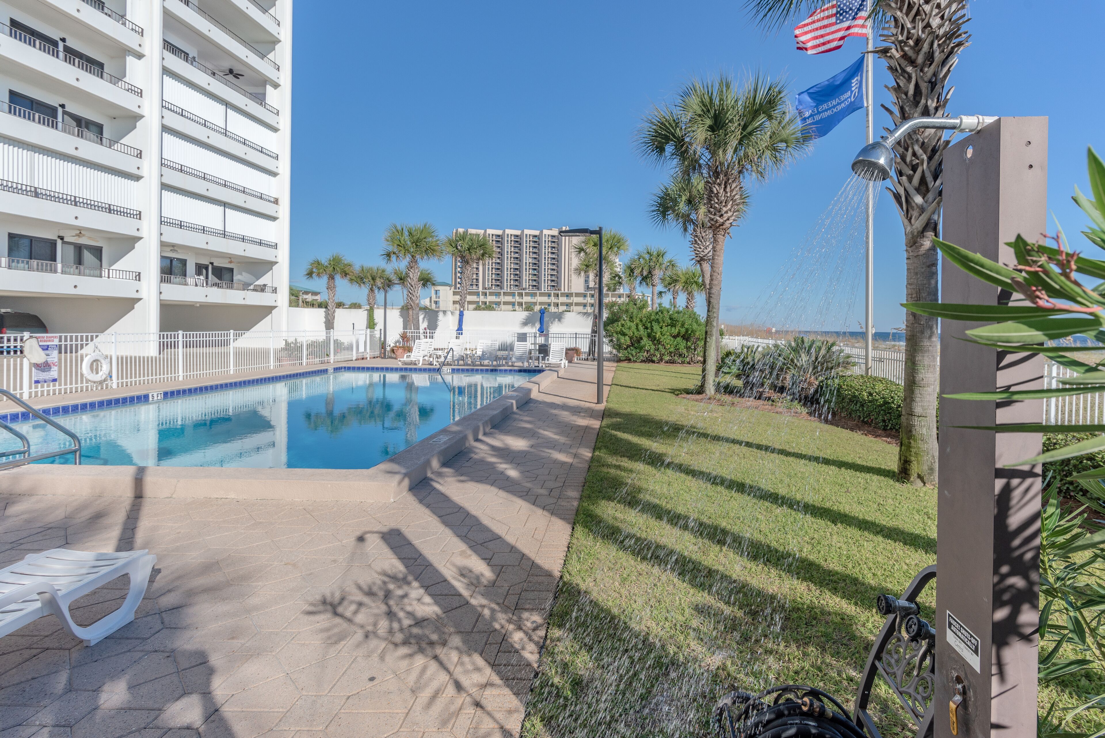 A swimming pool with lounge chairs, palm trees, and a view of a high-rise building.