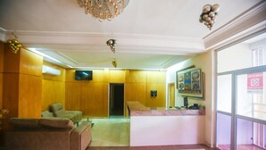 A lobby with a reception desk, a sofa, and a television. - Complexe Hôtelier Akparo (Dabou)