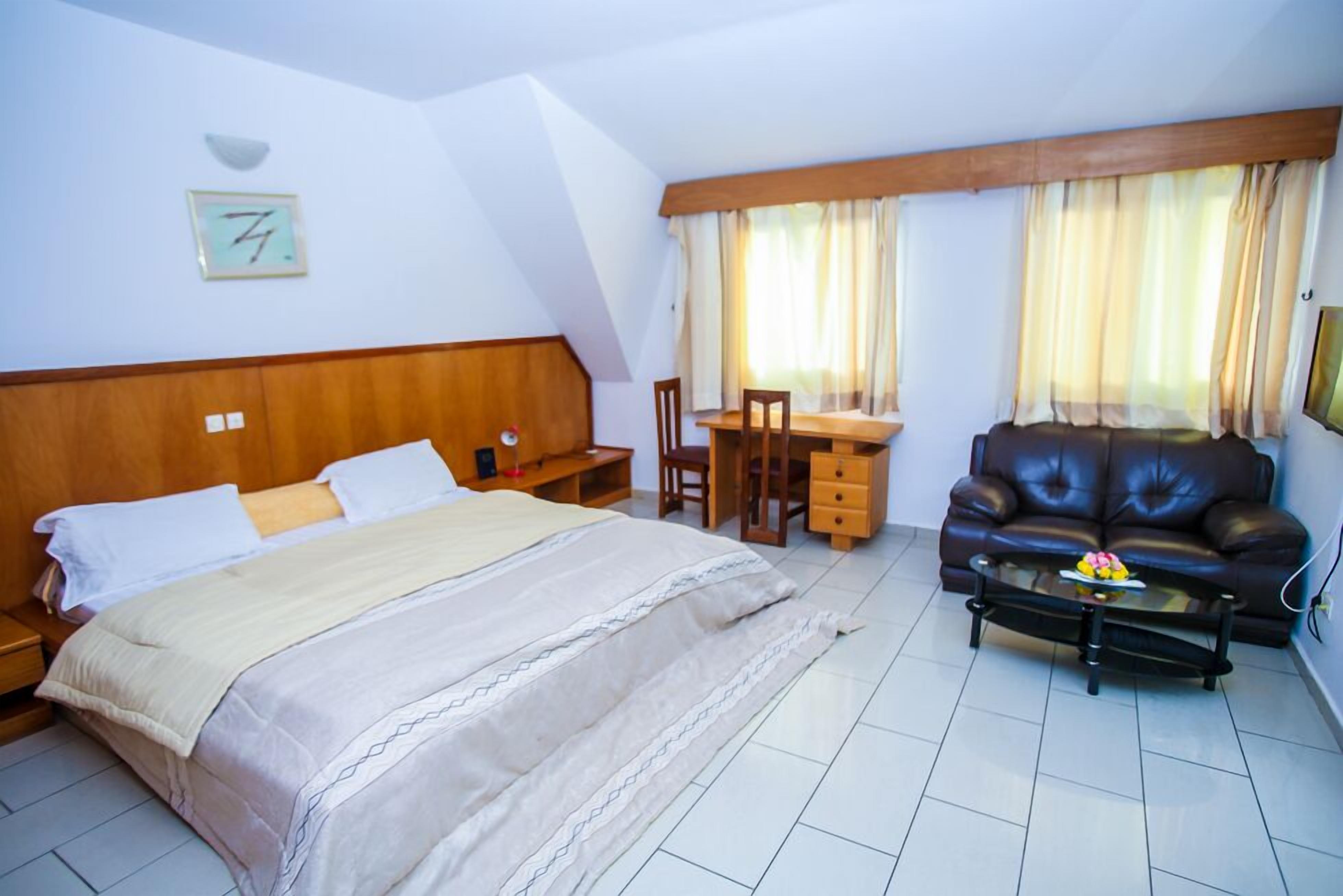 Un dormitorio con cama, escritorio, sofá de cuero y mesa de centro.