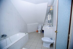 Een moderne badkamer met een bad, toilet en hygiëneschuimer.