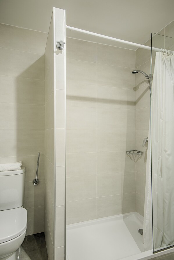 A modern bathroom with a glass-enclosed shower, a toilet, and a shower curtain.