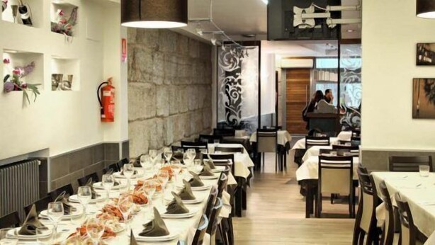 Un restaurant avec de longues tables dressées pour le repas, un extincteur accroché au mur et des œuvres d’art qui décorent les murs.