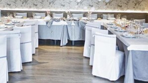 Une salle à manger élégante, avec des tables rondes dressées pour le repas, des nappes blanches et des chaises.