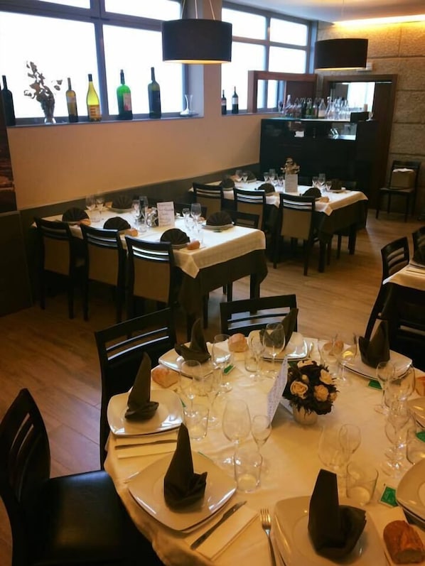 A restaurant with multiple tables set for dining, each with white tablecloths, wine glasses, and neatly folded napkins. - Hostal Restaurante Lugano (Verín)