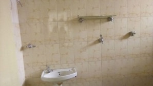 Un baño con lavamanos, un espejo y un estante sobre el espejo.