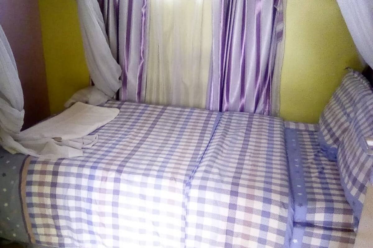 A bedroom with a checkered bedspread, a white blanket, and a canopy.