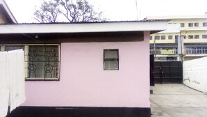 Un edificio de fachada rosa, una ventana pequeña y una reja de metal.