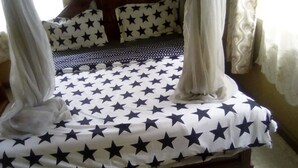 Una cama con colcha estampada de estrellas, un dosel y almohadas con un diseño similar.