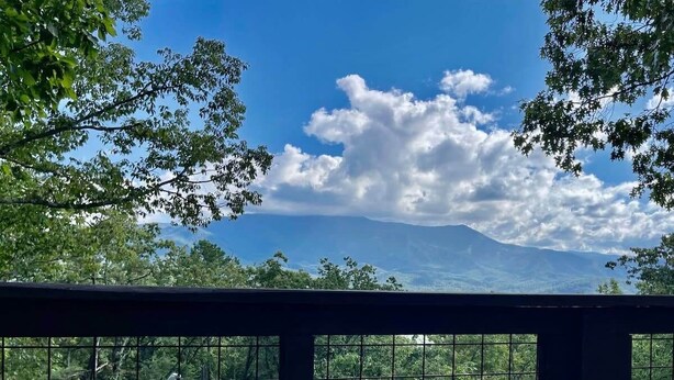 Un bain à remous sur un balcon avec vue sur une montagne et des arbres.