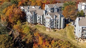 Ein mehrgeschossiges Wohngebäude mit moderner Architektur, gelegen in einer hügeligen Landschaft mit Herbstlaub.