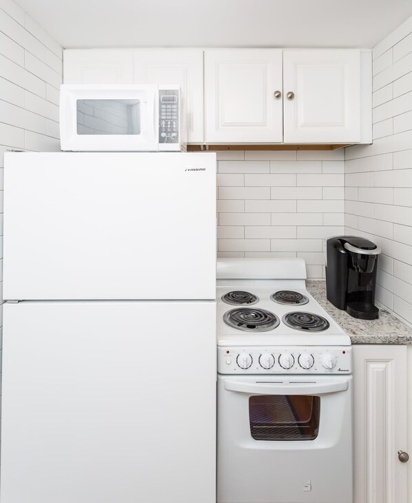A kitchen with a white refrigerator, stove, and microwave.