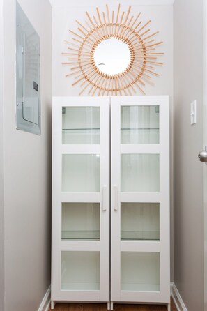 A white cabinet with frosted glass doors and a sunburst wall decoration above it.