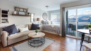 Een moderne woonkamer met een bank, een ronde salontafel en uitzicht op de omgeving door een groot raam.