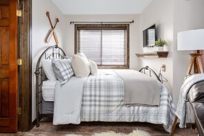 A bedroom with a bed, a window with blinds, a mounted television, and a bedside lamp. - Amazing Views Of Mt. LeConte/Indoor Pool & Hot Tub (Gatlinburg)