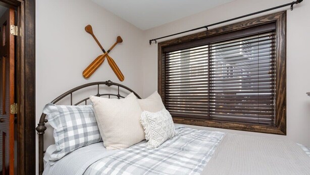 Ein Schlafzimmer mit einem Bett, einem Fenster mit Jalousien und zwei Schlägern an der Wand.