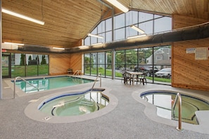 An indoor swimming pool area with multiple pools, a seating area, and large windows. - Amazing Views Of Mt. LeConte/Indoor Pool & Hot Tub (Gatlinburg)