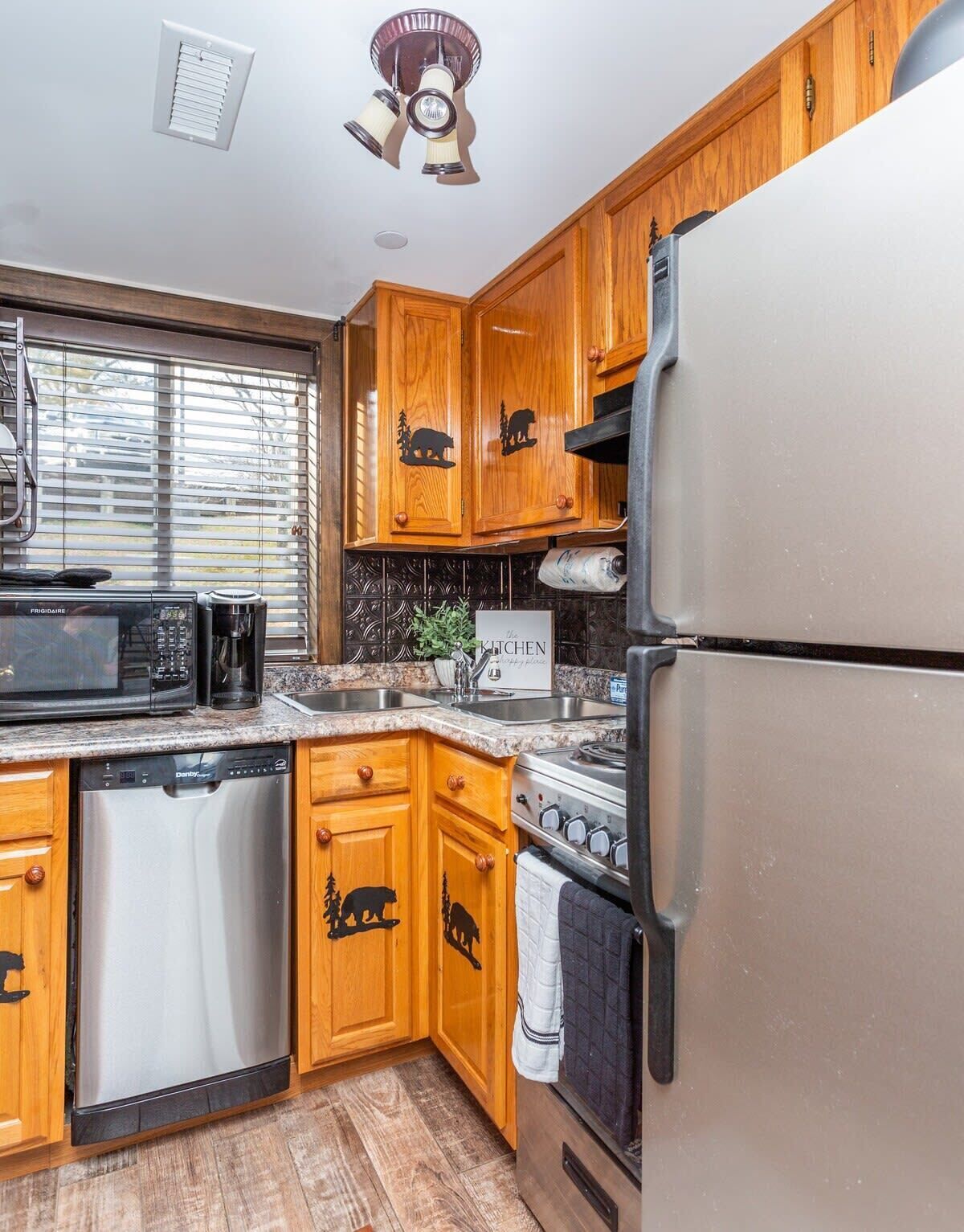 A kitchen with wooden cabinets, a stainless steel refrigerator, a stove, a dishwasher, and a microwave.