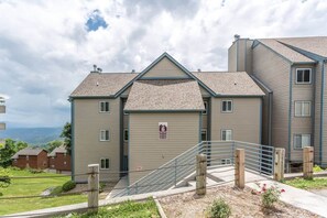 A multi-story residential building with a fire escape, a gated entrance, and a view of the surrounding landscape. - Amazing Views Of Mt. LeConte/Indoor Pool & Hot Tub (Gatlinburg)