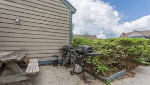 Eine Terrasse mit einem Holztisch und zwei Grillanlagen.