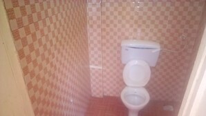 A small bathroom with a toilet and a checkered wall pattern. - Spanish Restaurant and Lodge Gilgil (Gilgil)