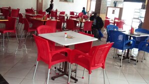 A dining area with red and blue chairs, white tables, and a tiled floor. - Spanish Restaurant and Lodge Gilgil (Gilgil)