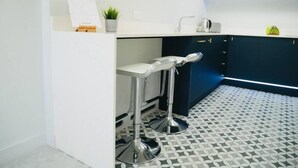 A modern kitchen with white countertops, a black and white patterned floor, and two bar stools. - ❤️❤️❤️❤️❤️Sea View, Walk 2 BEACH, Parking, Netflix (Bournemouth)