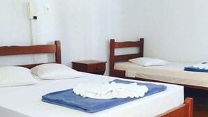 Una habitación con dos camas de madera, ropa de cama blanca y una toalla azul sobre la cama.