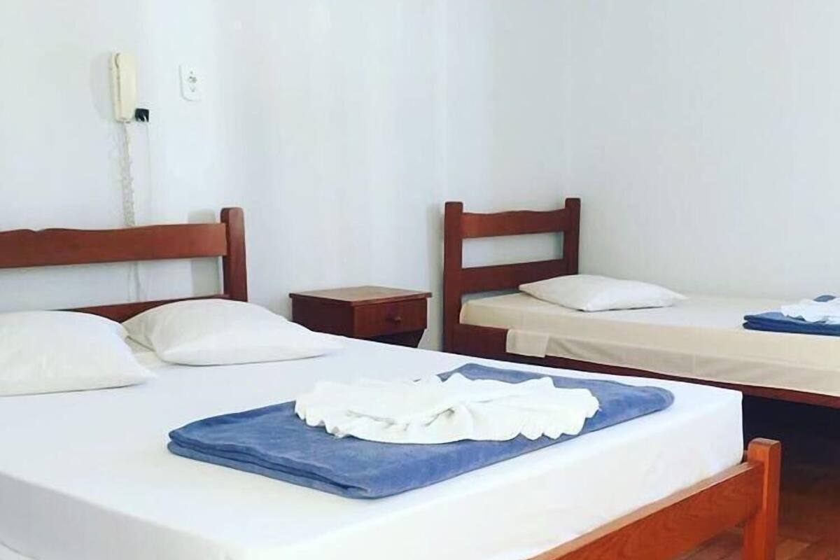 Une chambre d’hôtel avec deux lits en bois, du linge de lit blanc et une serviette bleue posée sur l’un des lits.