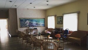 Un vestíbulo amplio con sillas de mimbre, una mesa redonda y un cuadro grande en la pared.