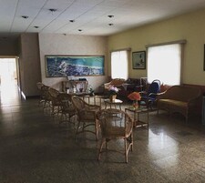 Um hall amplo com cadeiras de vime, uma mesa redonda e uma pintura grande na parede.