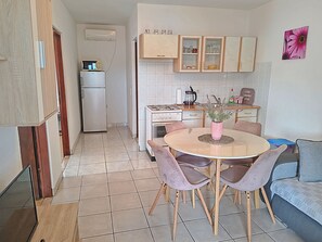A compact kitchen with a dining area, a refrigerator, a stove, and cabinets. - Apartments Pepa (Rogoznica)