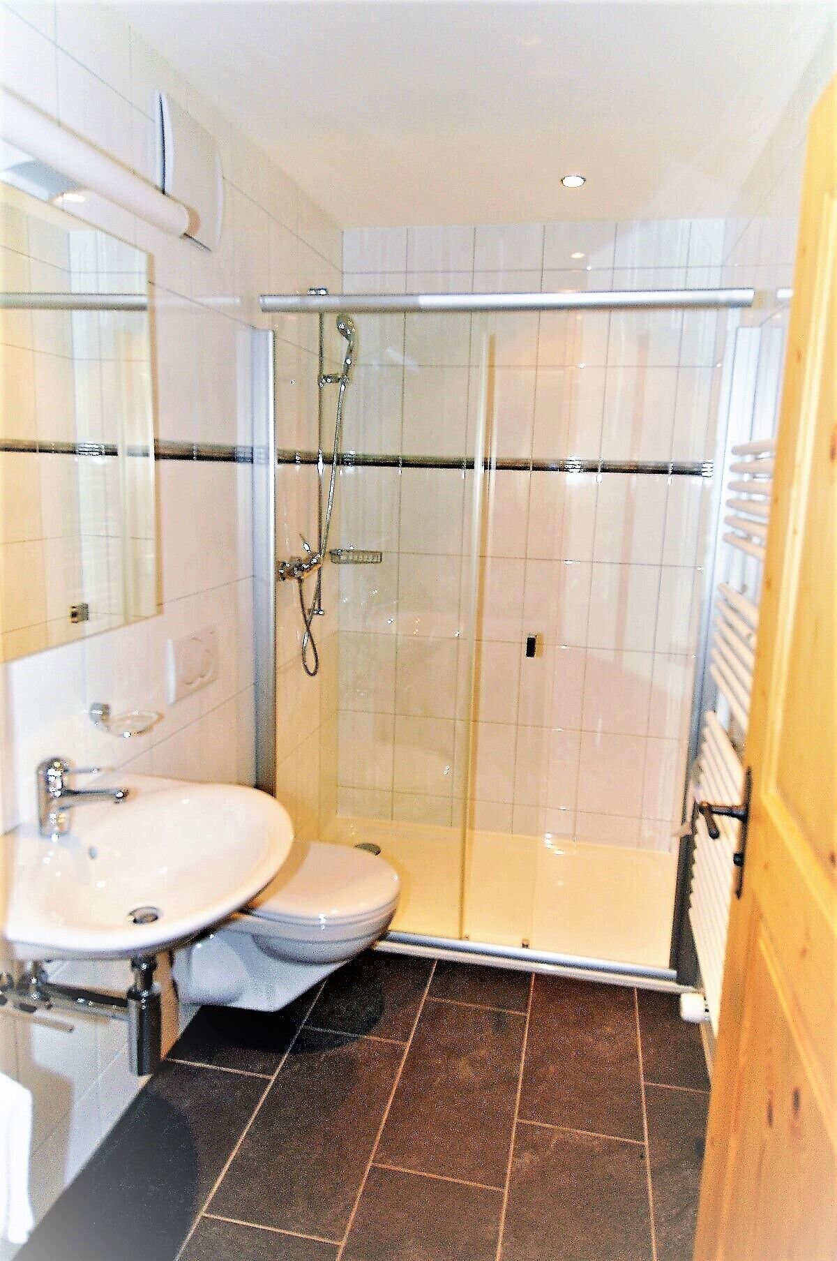 A bathroom with a glass-enclosed shower, a sink, and a toilet.