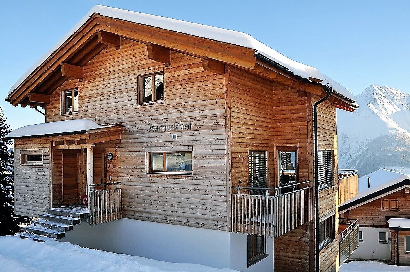 A wooden chalet with a balcony, a front entrance, and a sign reading "Aarinkhof".