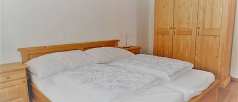 A bedroom with a wooden bed, a nightstand, and a wooden wardrobe.