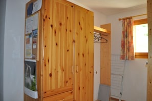 A wooden wardrobe with a mirror, a drying rack, and a window with curtains. - Alpengarten 4 (Bettmeralp)
