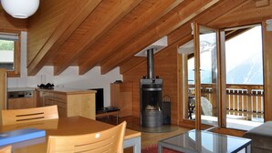 Una cabaña acogedora con interior de madera, una zona de cocina, una mesa de comedor y una chimenea.