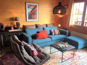 Ein gemütliches Wohnzimmer mit einem blauen Sofa, einem gemusterten Teppich und einem Couchtisch.