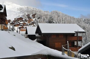 A snow-covered mountain village with wooden buildings, including a prominent lodge with a balcony. - Ambiente B12 (Bettmeralp)