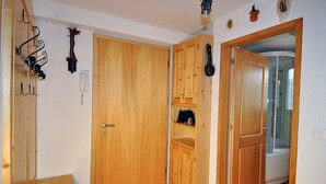 Un corridoio con porte in legno, un appendiabiti e una piccola mensola con oggetti.