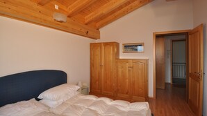 A bedroom with a bed, wooden wardrobe, and a door leading to another room. - Ambiente B21 (Bettmeralp)